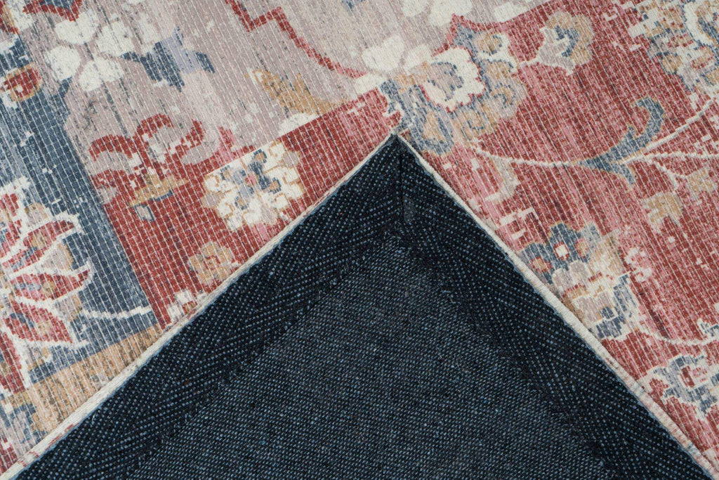 Ein rechteckiger bunter Teppich in Vintage Look liegt in einem Wohnzimmer. Rückseite