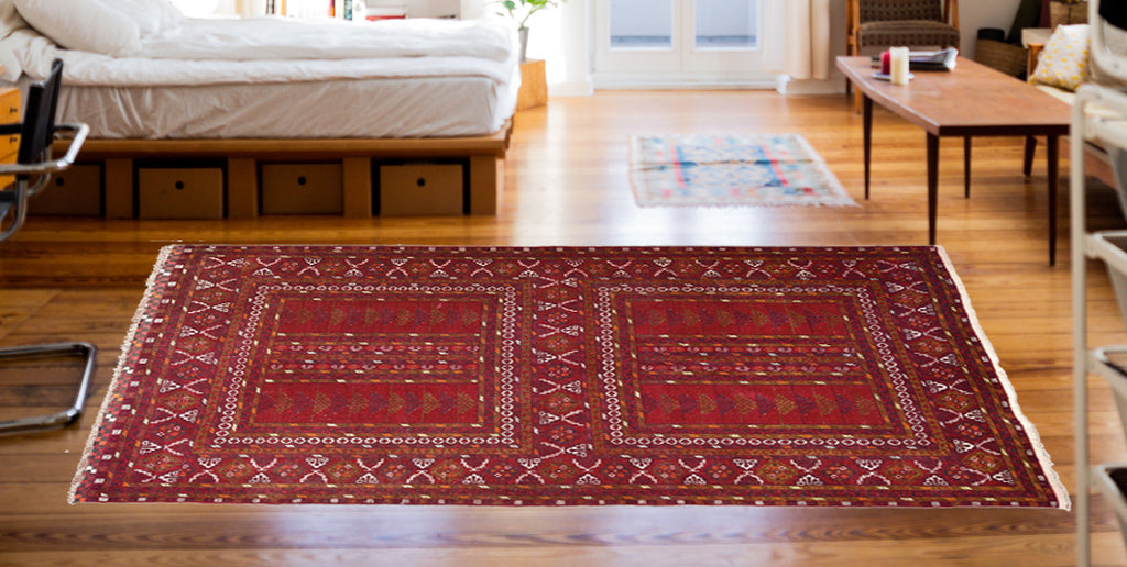 Afghanischer Teppich in rote Farbe liegt im Schlafzimmer
